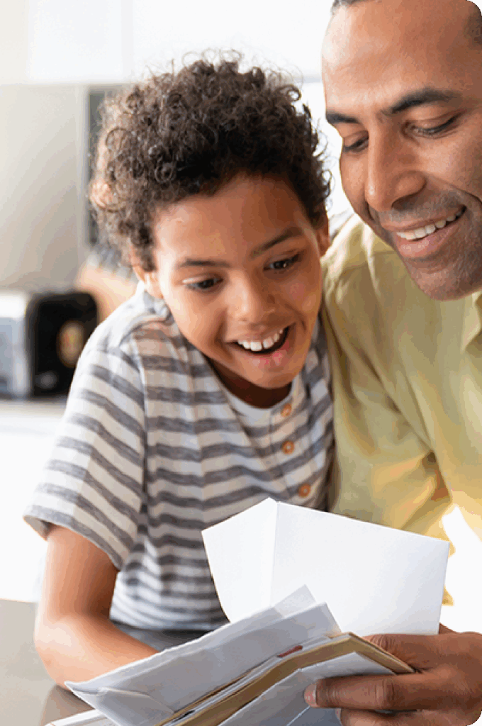 Man and young boy staring at a stack of envelopes, smiling